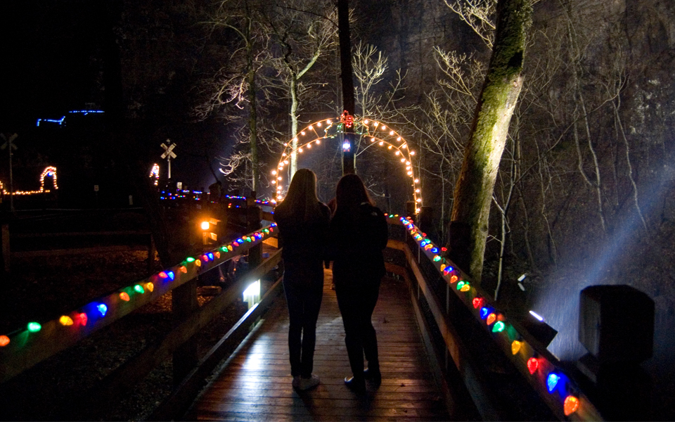 Two girls walking down path lit by holiday lights
