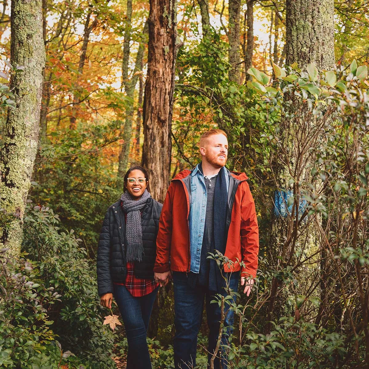 Couple walking hand in hand on a blue-blazed forest trail surrounded by autumn foliage in Southwest Virginia