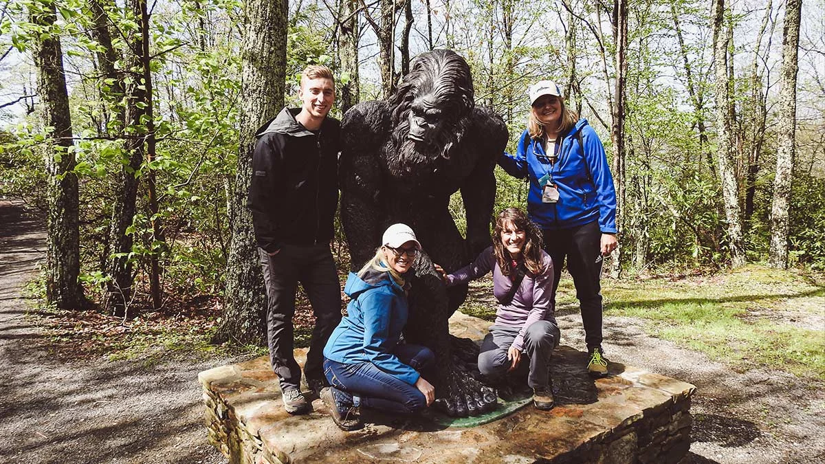Four visitors posing with the Woodbooger Bigfoot statue at Flag Rock Recreation Area in Norton, Virginia