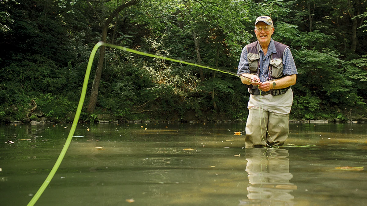 Two anglers fly fishing in a river, one holding a net with a caught fish, in Southwest Virginia