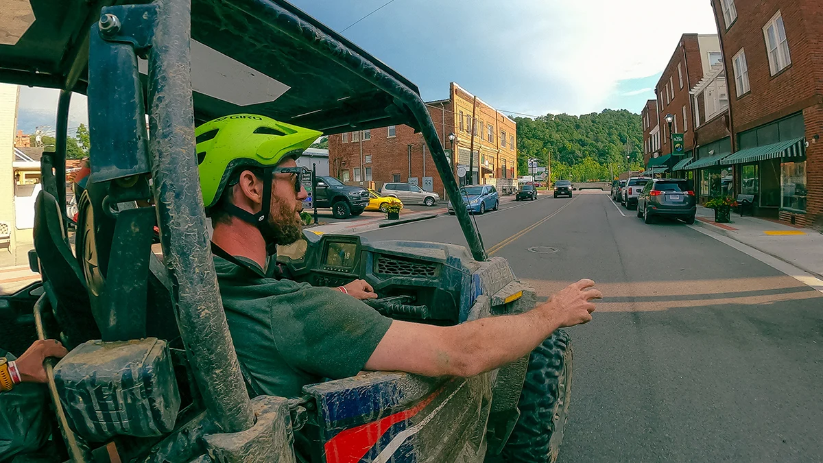 atv-utv-street-legal-driving-st-paul-virginia.jpg A driver wearing a green helmet operates a blue Polaris side-by-side UTV on the ATV-friendly main street of downtown St. Paul, Virginia.