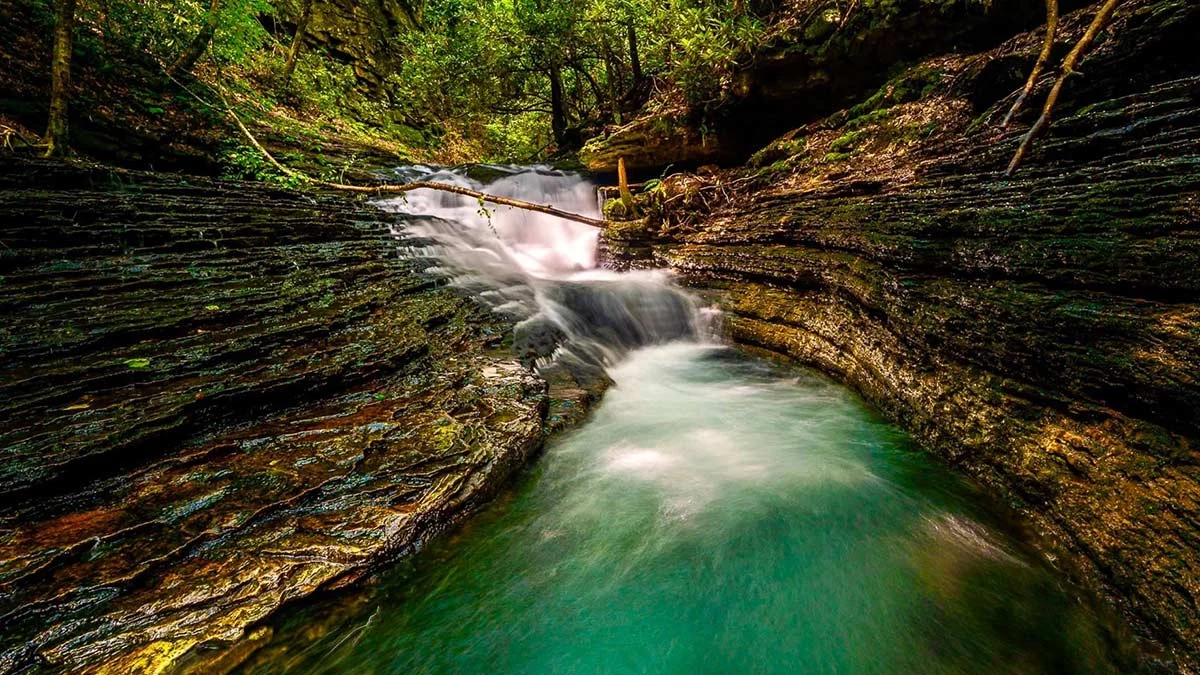 Turquoise water rushing through the carved rock chute of the Devil's Bathtub in Scott County, Southwest Virginia
