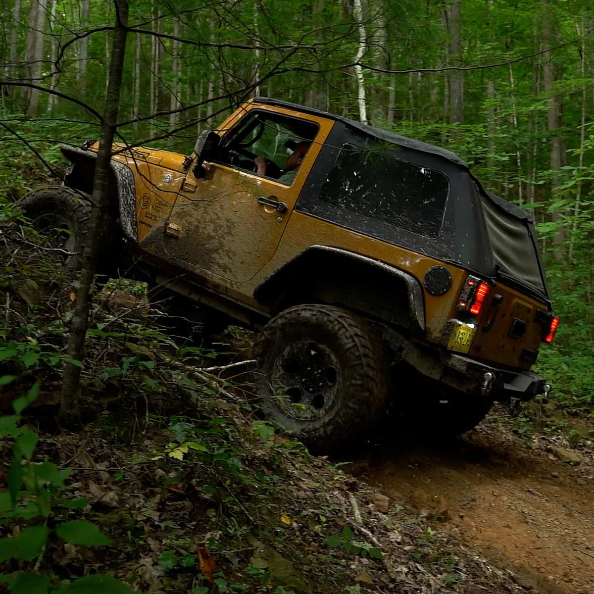jeep-4×4-offroad-jawbone-trail-richlands-tazewell-county-va.jpg A mud-splattered yellow Jeep Wrangler climbs a steep, rugged dirt incline on the Jawbone Trail System in Richlands, Tazewell County, Virginia.