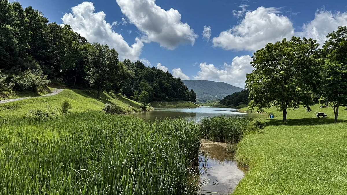 Scenic lake ringed by green lawn and forested ridges at Lincolnshire Park, along the Patriot Trail in Tazewell County.