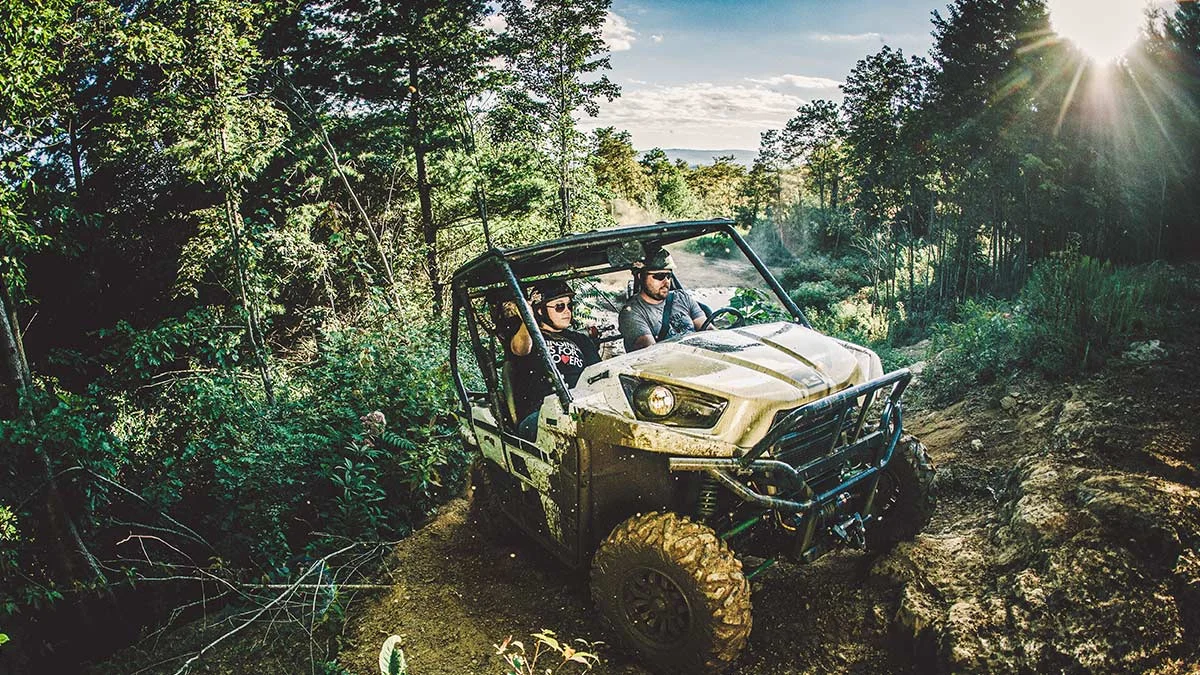 Two riders driving a side-by-side UTV up a rugged mountain trail in Southwest Virginia
